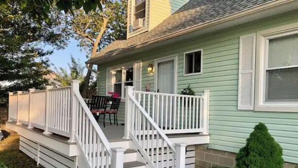 A two-story house with a front porch, a staircase, and a small garden area. - Bungalow by the Bay (Villas)