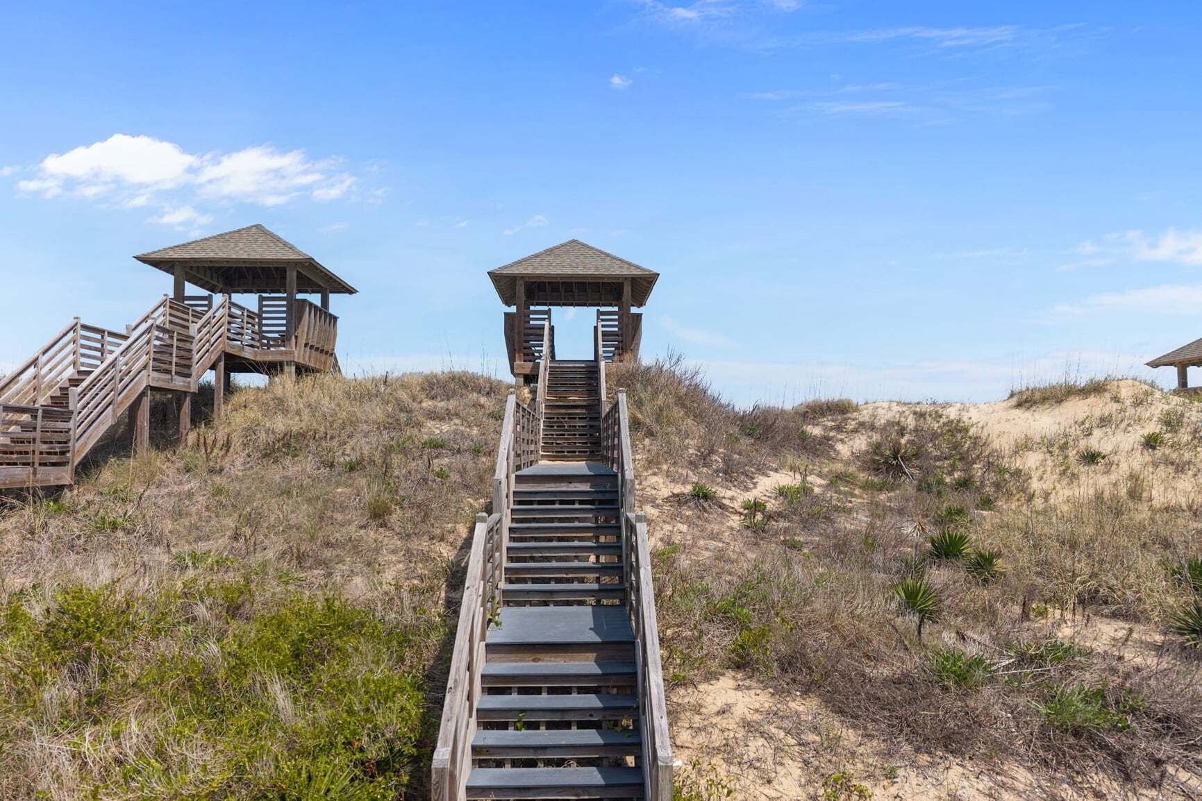 A wooden staircase leading to a beach with two lookout towers.