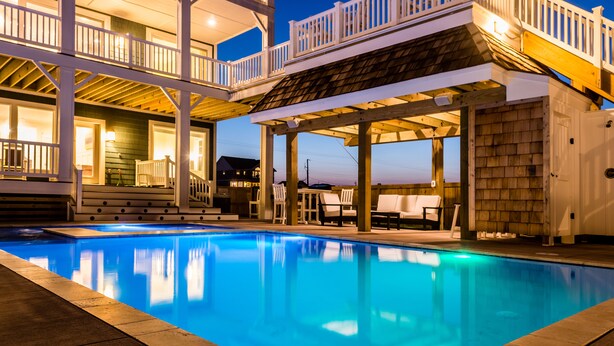 A swimming pool with a covered patio area, a multi-level deck with railings, and outdoor seating. - 5410- Ocean Star - Oceanfront Nags Head Luxury Home w/ Pool (Nags Head)