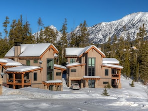 A wooden lodge with multiple rooms, a covered driveway, and a view of snow-covered mountains. - 8 Claim Jumper | Slopeside Chalet, Hot Tub, Sleeps 18 (Big Sky)