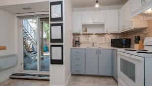 A modern kitchen with white cabinets, a built-in microwave, and a stove. - ESPACE COURONNE QUEBEC (La Cité-Limoilou)