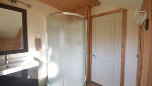 Un baño con cabina de ducha de vidrio, lavamanos y puerta.