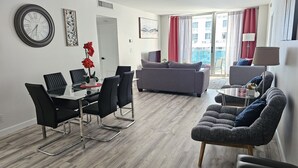 A modern living room with a dining area, grey sofas, and a glass table. - Beautiful Ocean-View, 16th floor, apartment, right ON THE Beach.  (Hollywood)