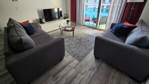 A modern living room with two grey sofas, a flat-screen TV, a coffee table, and a patterned rug. - Beautiful Ocean-View, 16th floor, apartment, right ON THE Beach.  (Hollywood)
