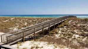 A wooden boardwalk leading to the beach, surrounded by sand dunes and sparse vegetation. - Gulf Front Luxury - Private Elevator/5 Master bdrms - each w/private bath  (Navarre)