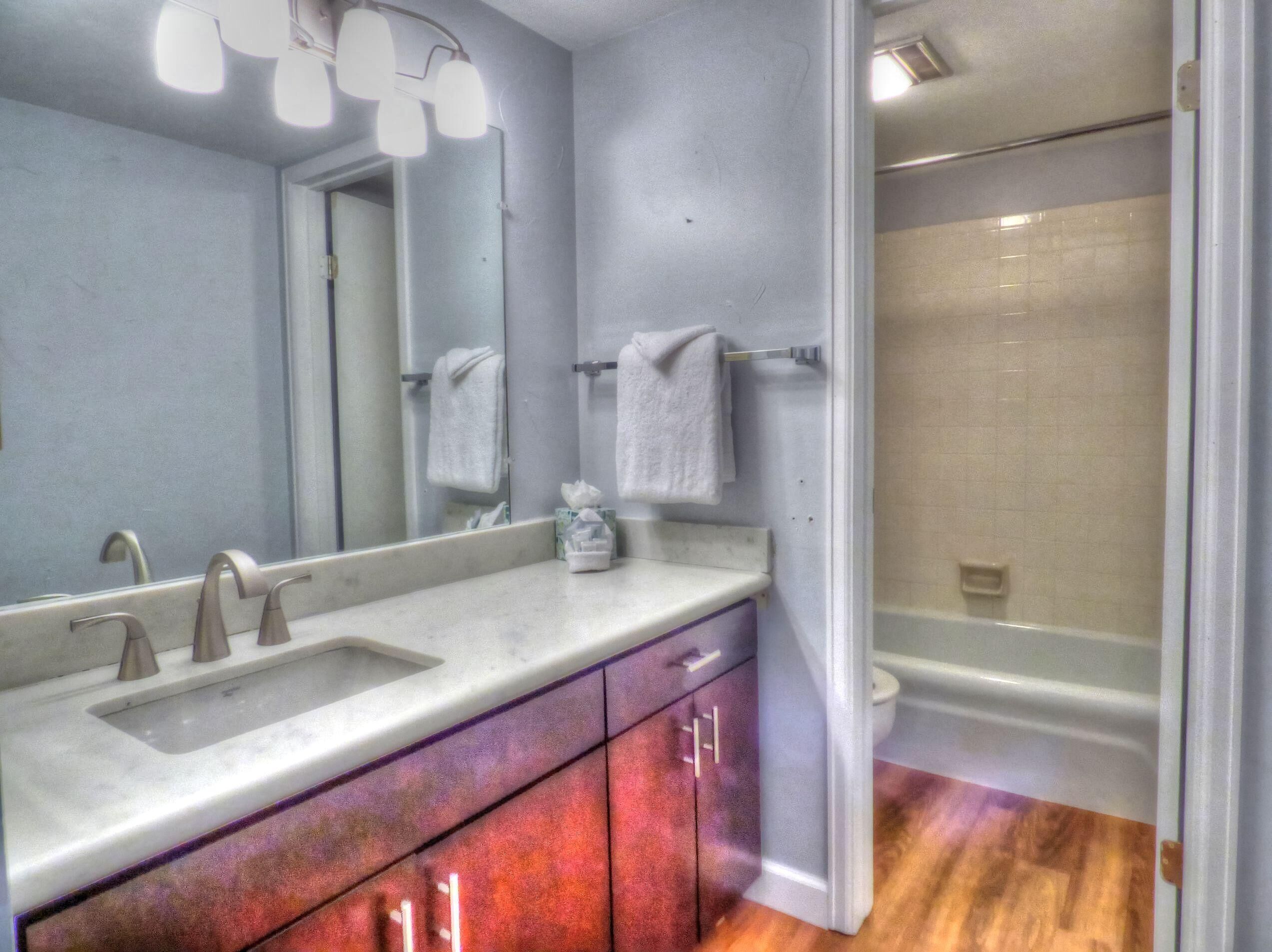 A bathroom with a double sink, a large mirror, a towel rack, and a shower area.