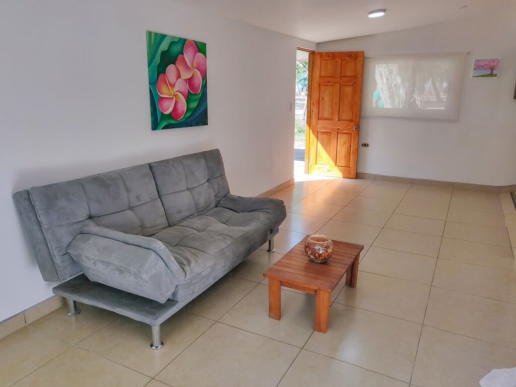 Ein Wohnzimmer mit grauem Sofa, einem Holztisch und einem Blumenbild an der Wand.