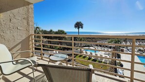 Un balcón con vista a una piscina y una playa.