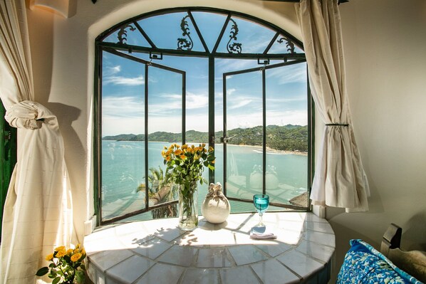 Enjoy a serene coastal view from the arched window, surrounded by a decorative metal gate.