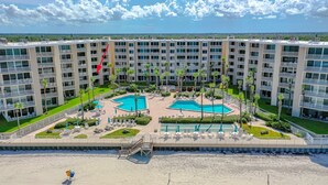 A multi-story hotel with a rooftop pool area, including two swimming pools and sun loungers. - BREATHTAKING OCEAN VIEWS & UPDATED CONDO  (New Smyrna Beach)