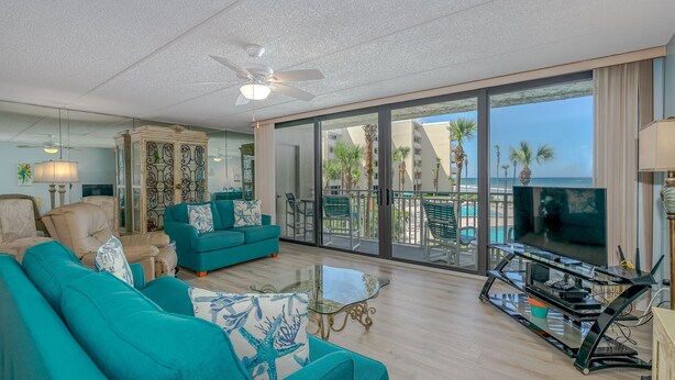 A spacious living room with teal sofas, a glass coffee table, and a TV on a stand. - BREATHTAKING OCEAN VIEWS & UPDATED CONDO  (New Smyrna Beach)