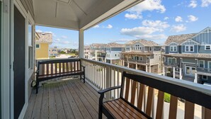 Une terrasse en bois avec un banc, d’où l’on peut admirer une rangée de maisons de ville sous un ciel d’un bleu éclatant.