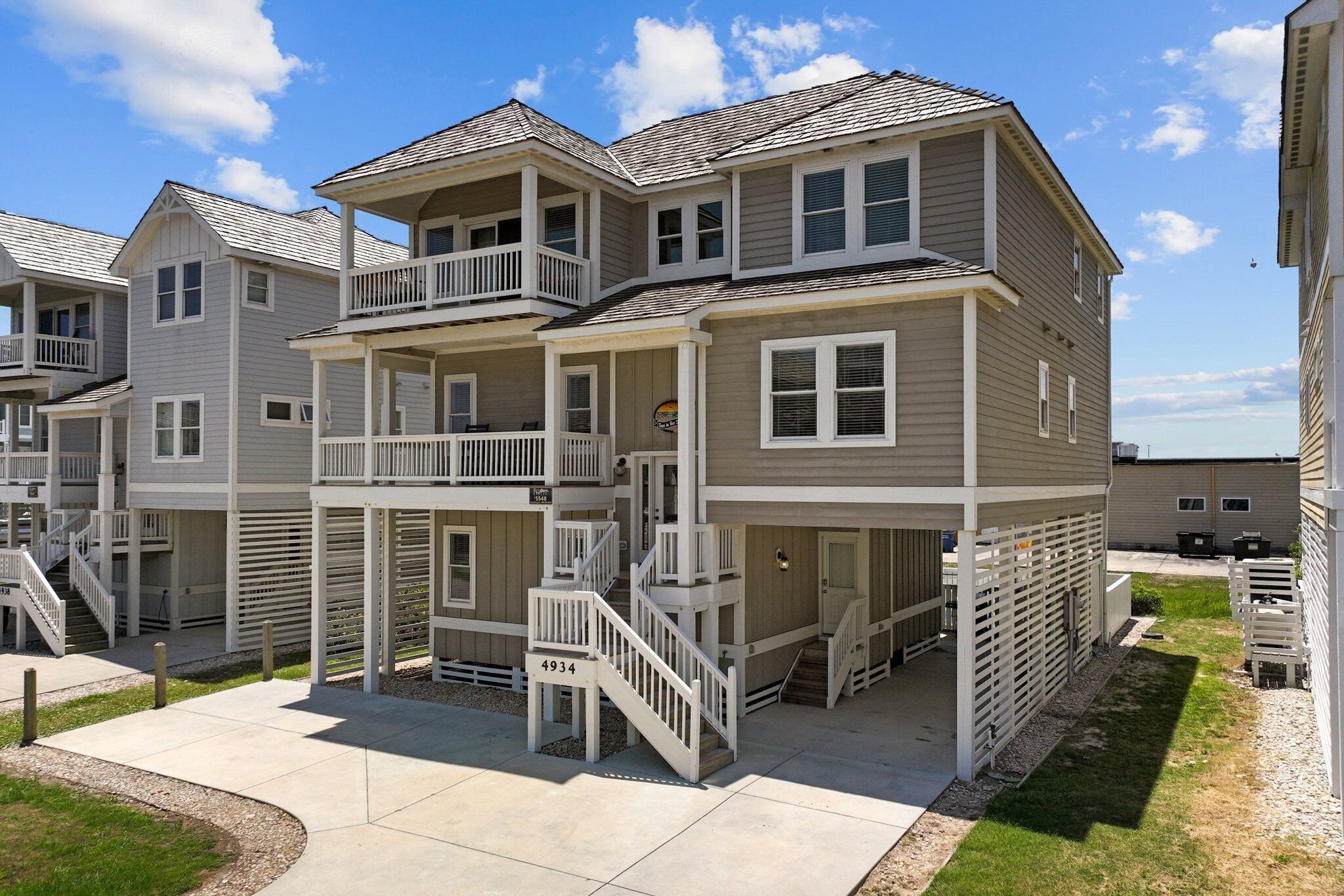 A multi-story residential building with a balcony, a covered patio, and a staircase leading to the upper floors.
