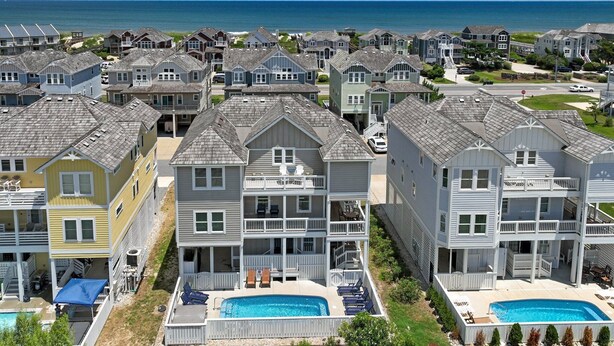 Un quartier résidentiel situé sur la côte, composé de plusieurs maisons à deux étages, d’une piscine et offrant une vue sur l’océan.