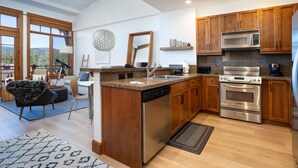 Eine moderne Küche mit Holzschränken, Edelstahlgeräten und einer großen Kochinsel mit Geschirrspüler.
