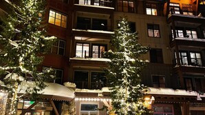 Ein mehrstöckiges Hotel mit Steinverkleidung, Balkonen und beleuchteten Fenstern.