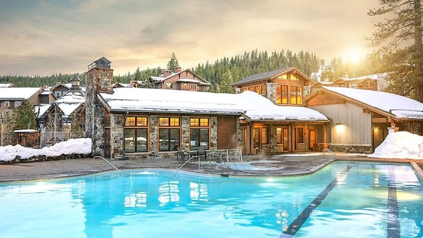 Ein Resort mit Schwimmbad, Steingebäuden und schneebedeckten Dächern.