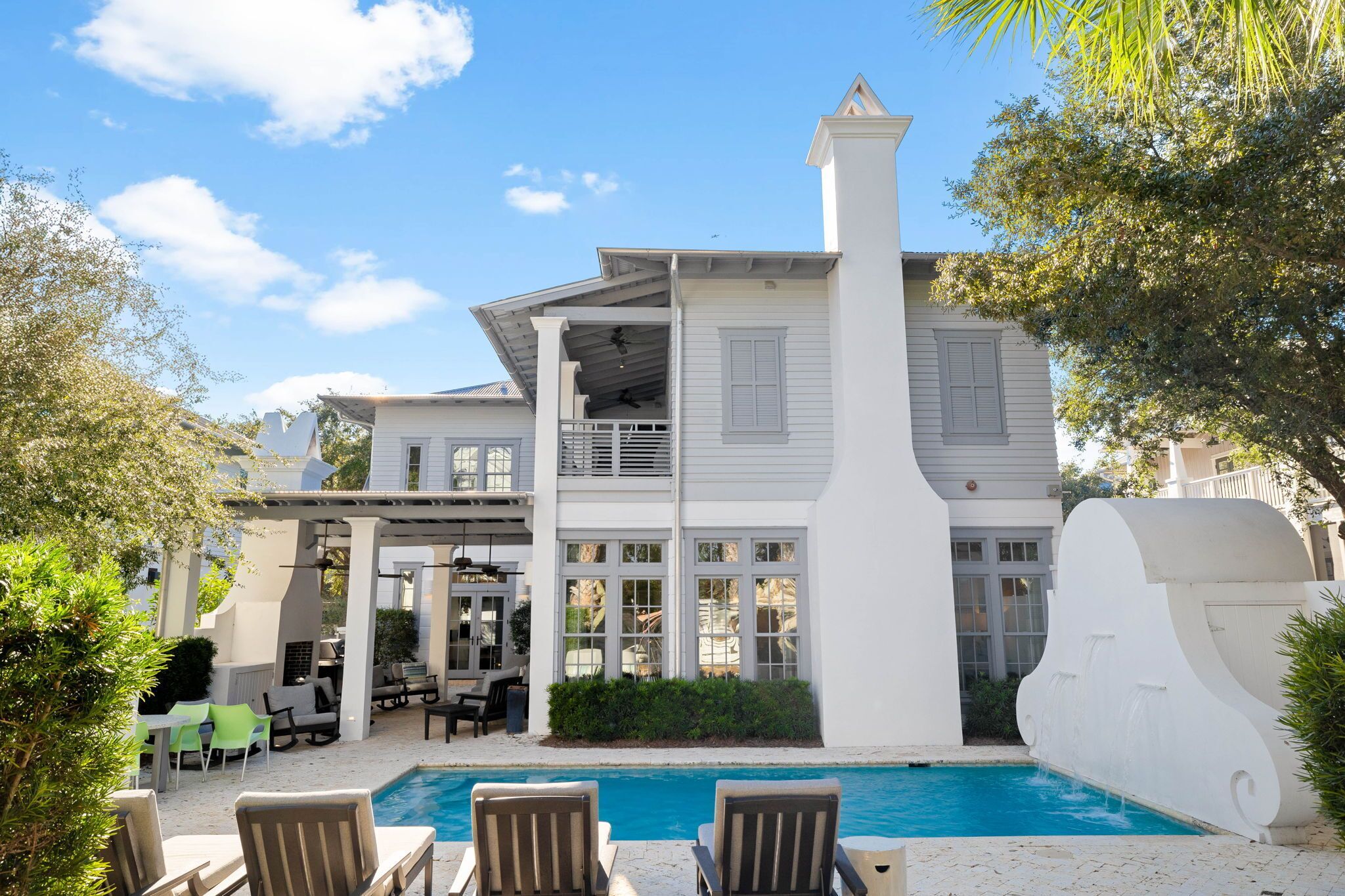 A two-story house with a pool, outdoor seating, and a covered patio area.