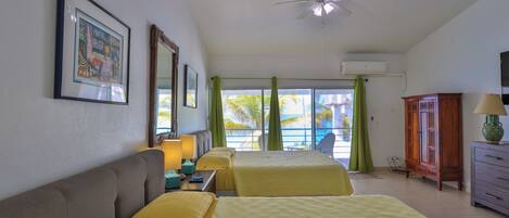 A hotel room with two beds, a ceiling fan, a large window with curtains, a wooden cabinet, and a television.