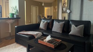 A modern living room with a black leather sofa, a coffee table, and a potted plant. - Heart of Downtown Edmonton, walking distance to Rogers Place / LRT station  (Edmonton)