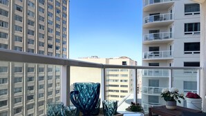 A balcony with a glass table, blue glassware, and a small plant. - Heart of Downtown Edmonton, walking distance to Rogers Place / LRT station  (Edmonton)