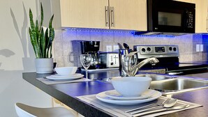 A modern kitchen with a granite countertop, stainless steel appliances, and a potted plant. - Heart of Downtown Edmonton, walking distance to Rogers Place / LRT station  (Edmonton)