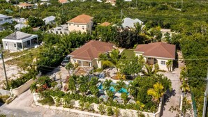 Zona residencial con dos casas, una piscina y abundante vegetación.