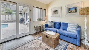 A living room with a blue sofa, a wicker coffee table, and a ceiling fan.