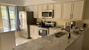 A modern kitchen with a large island, stainless steel appliances, and light-colored cabinetry.