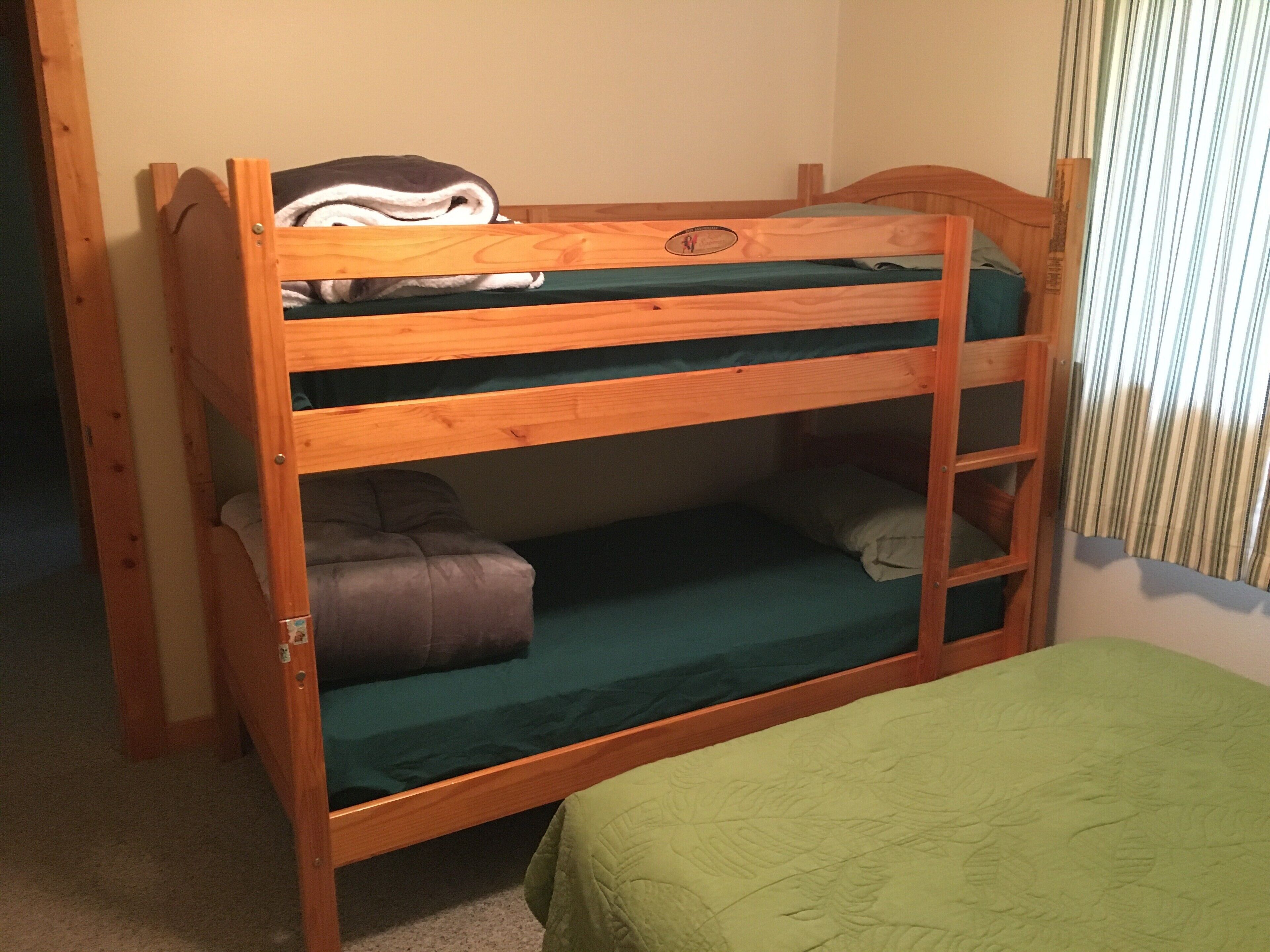 Een stapelbed met een groene matras en een kussen op het onderbed.