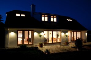 A modern house with large glass doors, a stone patio, and potted plants. - Nearwater B&B (Truro)