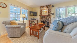 A living room with a fireplace, a television, and a stone wall.