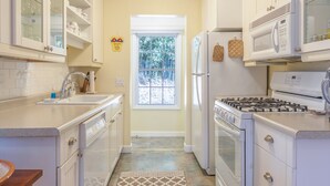A kitchen with white cabinets, a sink, a stove, a refrigerator, and a microwave.
