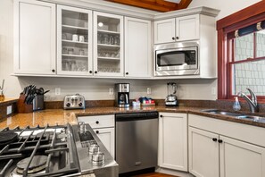 A modern kitchen with white cabinets, a stainless steel stove, a dishwasher, a coffee maker, and a microwave.
