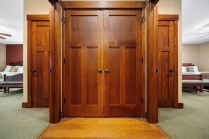 A room with a large wooden wardrobe, a bed with a headboard, and a carpeted floor.