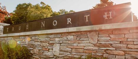 A stone wall with a sign that reads "TRUE NORTH".