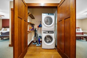 A laundry room with a front-loading washer and dryer, a mop, and cleaning supplies.
