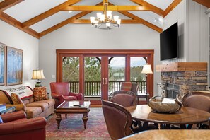 A spacious living room with a fireplace, a dining area, and a large sliding glass door leading to a balcony.
