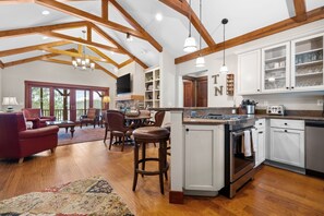 A spacious kitchen with wooden beams, a central island, and a dining area with leather chairs.