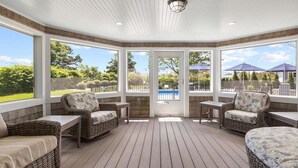 A covered patio with wicker furniture and large windows.