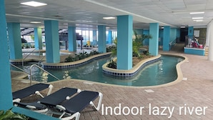An indoor lazy river with blue-tiled pools, lounge chairs, and potted plants. - Beautiful oceanview 1 bedroom with king bed, full kitchen, and water amenities  (Myrtle Beach)