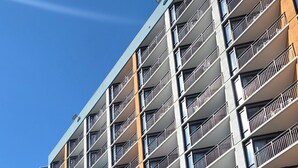 A multi-story hotel with balconies, a parking area, and palm trees. - Beautiful oceanview 1 bedroom with king bed, full kitchen, and water amenities  (Myrtle Beach)