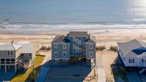 Une propriété située en bord de mer, comprenant une grande maison dotée de plusieurs terrasses et d’un patio couvert.