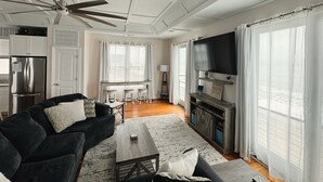 Un salon moderne avec un canapé foncé, une table basse, un téléviseur et une cheminée.