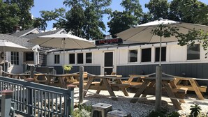 A restaurant with outdoor seating, wooden tables, and umbrellas. - Newly Renovated Near Amazing Sunset Beach (Falmouth)