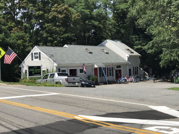 A building with a sign reading "Bike Zone of Cape Cod" and several bicycles parked outside.