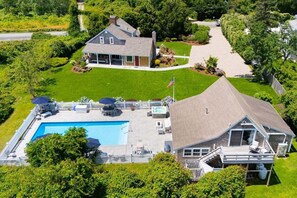 Uma casa grande com piscina, varanda coberta e gramado bem cuidado.