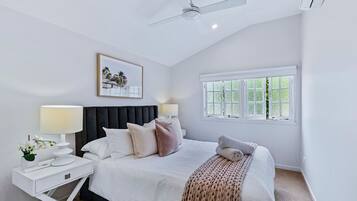 A bedroom with a bed, nightstands, a ceiling fan, a window, and a framed picture on the wall.