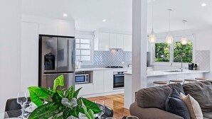 Eine moderne Küche mit weißen Schränken, einem Edelstahl-K ühlschrank und einer Fischgrät-Spruchplatte.