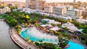 Ein Hotel direkt am Wasser mit einem zentral gelegenen Pool, umgeben von üppiger Vegetation und modernen Gebäuden.